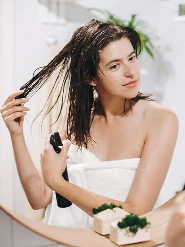 Slim sexy woman applying hair spray