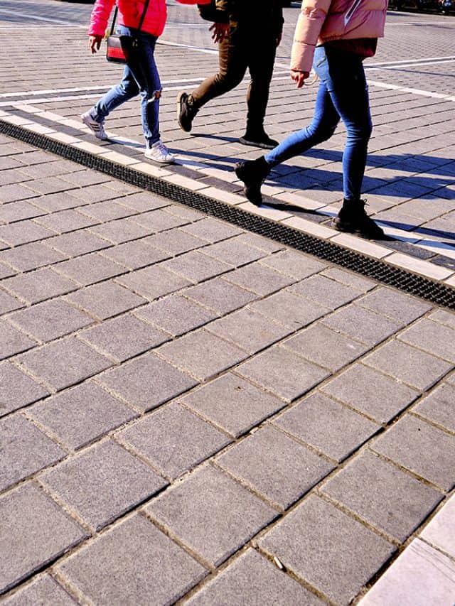 Three people walking on cobblestone streets wearing skinny jeans