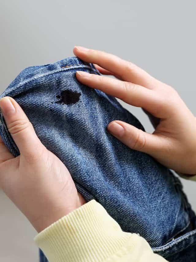Woman holding jeans with black oil stain