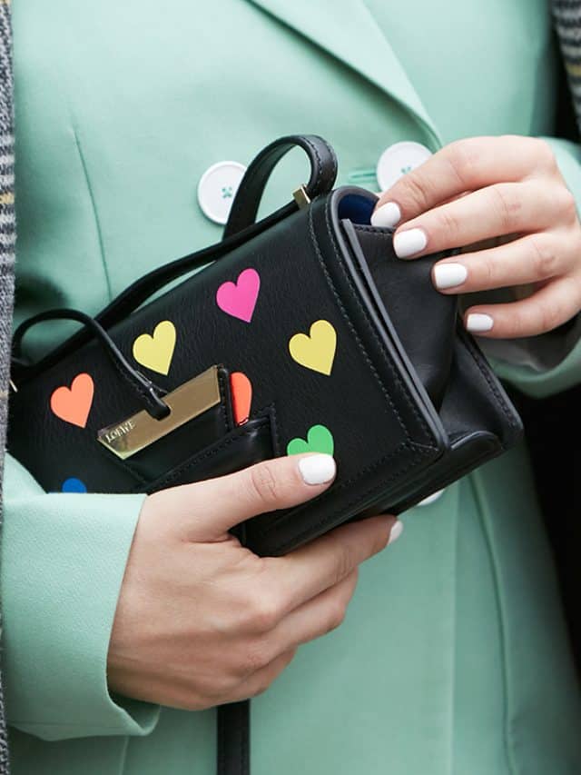 Woman with black leather Loewe bag with colorful hearts and pastel green jacket