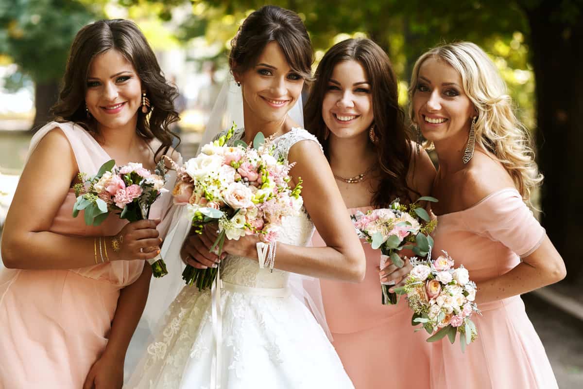 Bride with bridesmaids on the park on the wedding day
