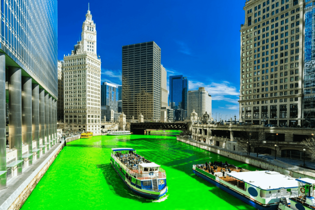 Photo is of the chicago river with the chicago skyline in the background. The river is dyed green for St. Patrick's Day