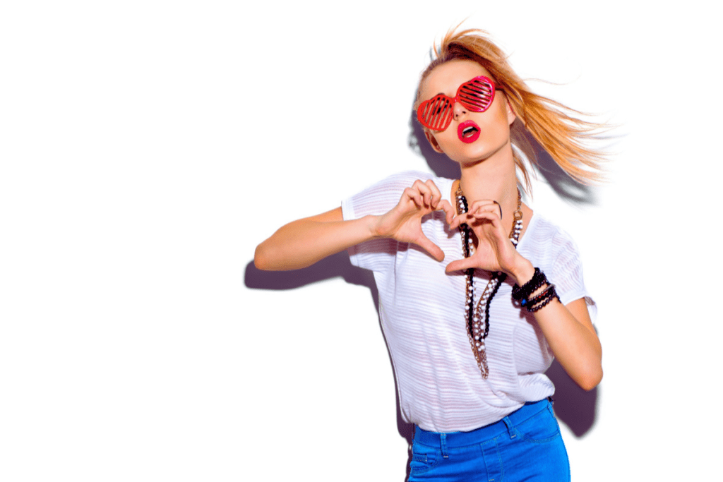 Fashion Model girl isolated over white background. Beauty stylish blonde woman posing in fashionable clothes and heart shaped sunglasses. Casual style with beauty accessories. High pony hair style
