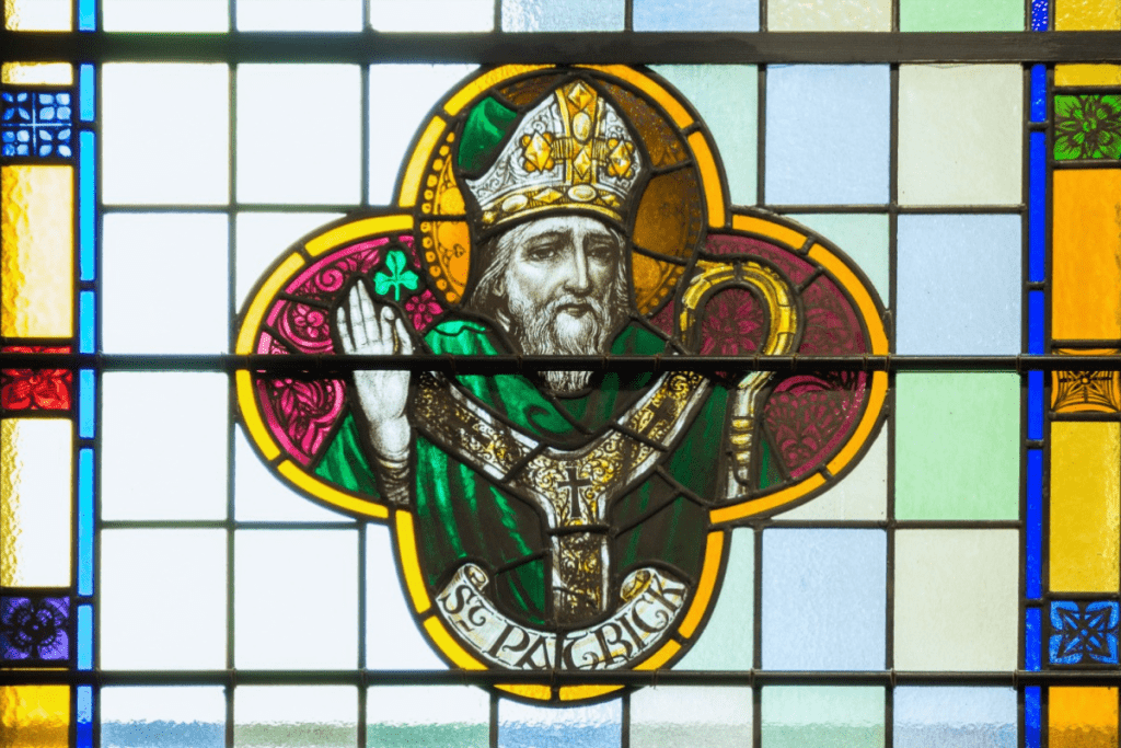 A stained glass window featuring the likeness of St. Patrick holding a clover leaf.