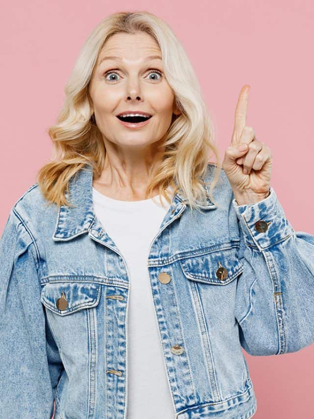 Elderly insighted fun happy woman 50s wearing denim jacket holding index finger up