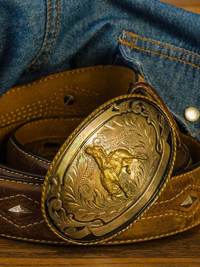 Vintage western belt buckle on rustic wood with denim shirt