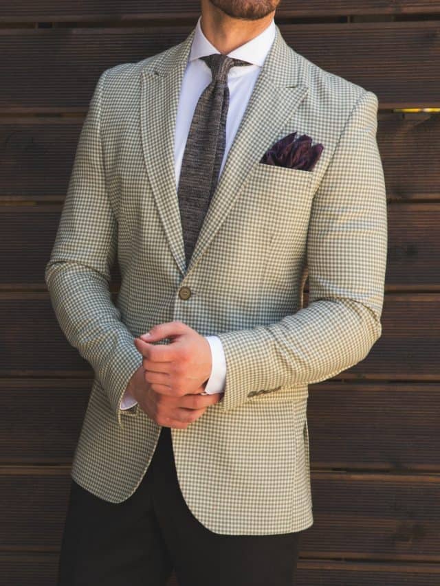 Male model in a suit posing in front of a wooden wall