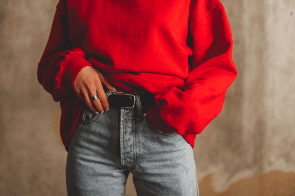 Image of woman wearing high waist pants with a belt and a red sweater
