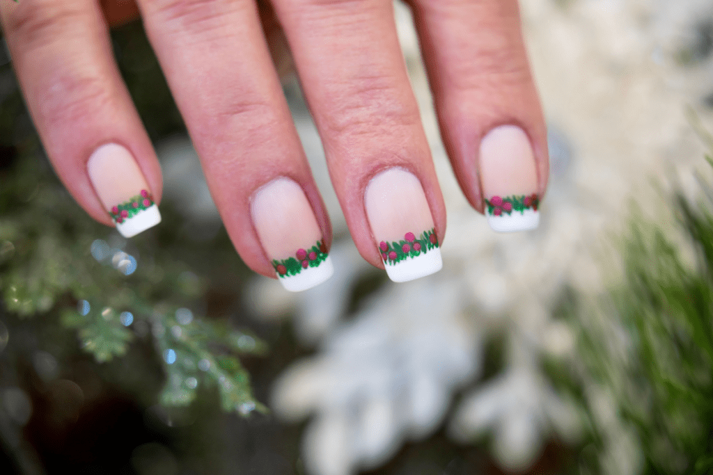 Image of a french manicure featuring christmas themed garland across the tip