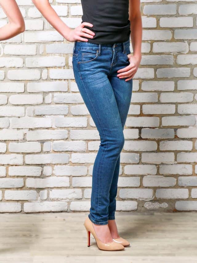 Close,Up,Female,Legs,In,Jeans,On,Brick,Wall,Background.