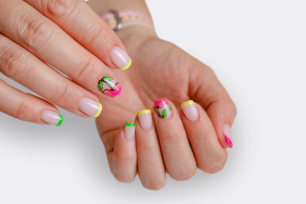 Image is of a french manicure featuring bright pink, green, or yellow tips and nail art with a cherry.
