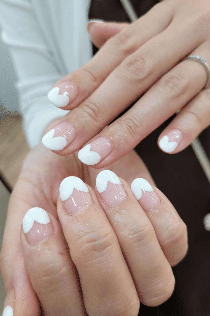 Image is of a french manicure that is a pink nail bed with a heart shaped white tip.