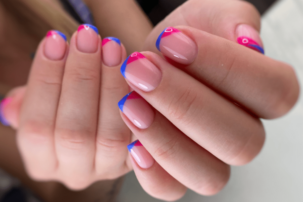 Image is of a french manicure. Each tip is half bright blue and half bright pink
