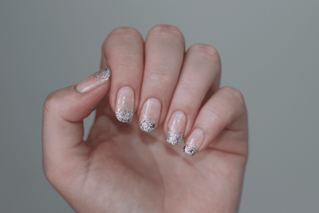 French manicure featuring a pink nail bed with glittery silver tips.
