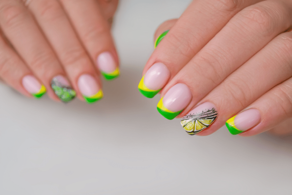 Image is of a french manicure featuring bring yellow and green tips with lemons as nail art.