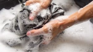 Woman washing a shirt with her hand, Remove Tire Marks From Clothes Like a Pro [How to Guide] - 1600x900