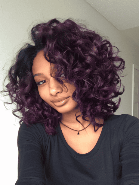 A woman with short curly hair in rich plum color