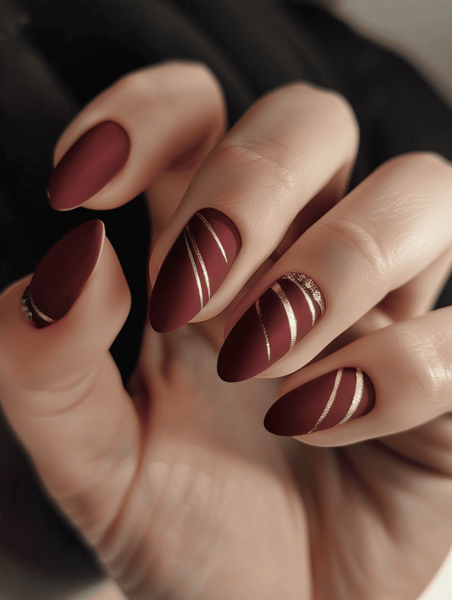 matte nail design in maroon with metallic stripes
