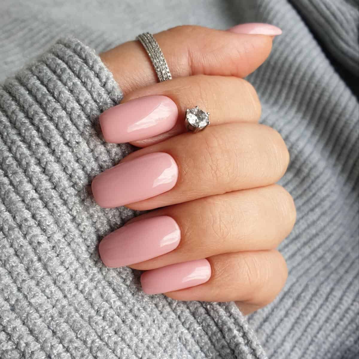 light pink manicure with gray textured sweater background 