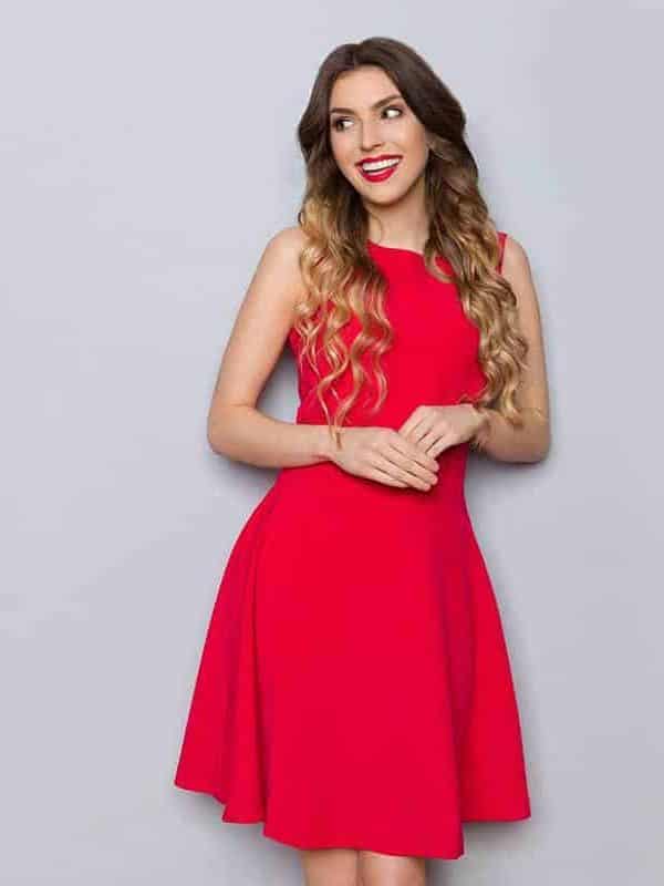Smiling beautiful young woman in elegant red dress posing and looking away